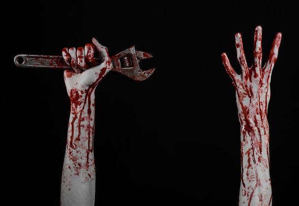 Halloween theme: bloody hand holding a big wrench on a black background - Fotoğraf, Görsel