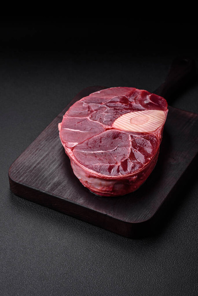 Friss marhahús ossobuco steak sóval, fűszerekkel és fűszernövényekkel texturált betonalapon - Fotó, kép