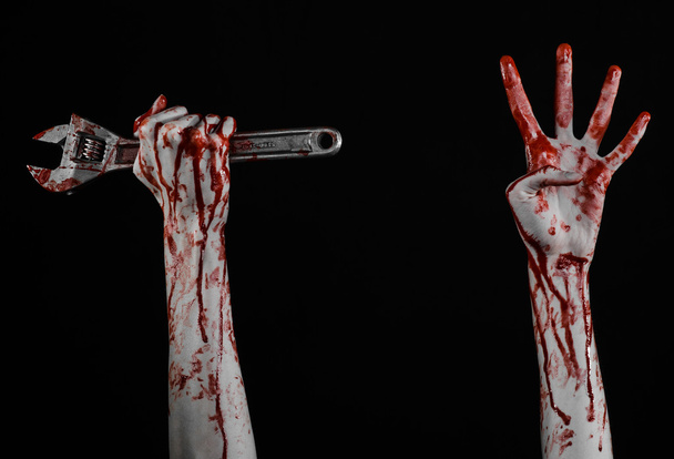 Halloween theme: bloody hand holding a big wrench on a black background - Фото, зображення