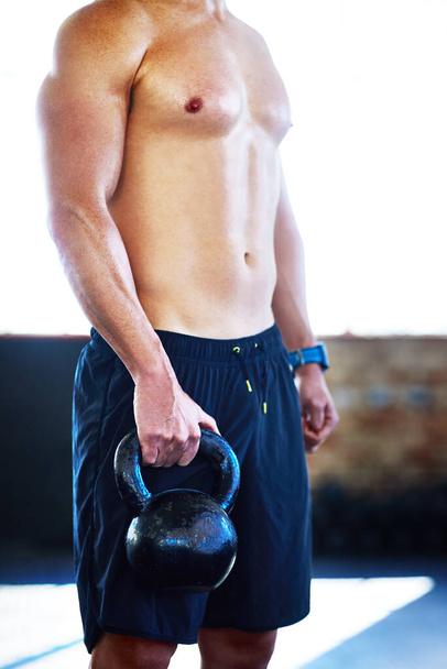 Working on my muscles. an unrecognizable man lifting kettlebells in a gym - Φωτογραφία, εικόνα