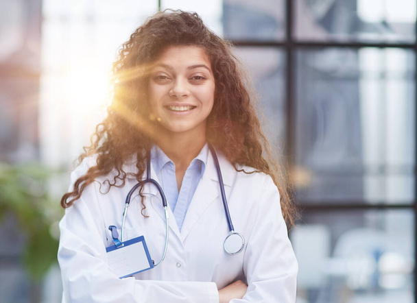 Portrait of young woman doctor with white coat standing in hospital - Foto, afbeelding