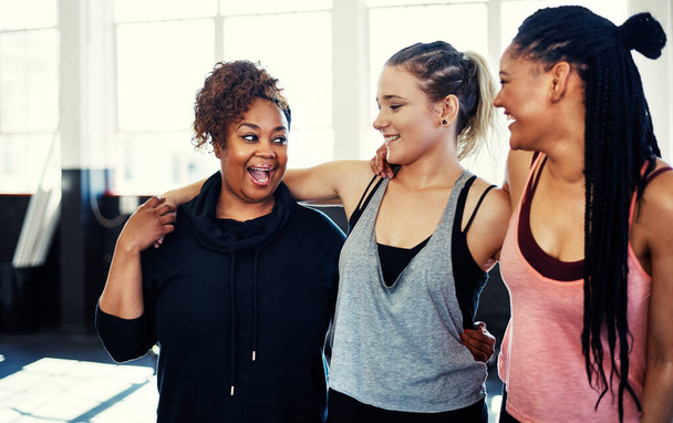 We feel great already. three cheerful young women having a conversation while holding each other before a workout session in a gym - 写真・画像
