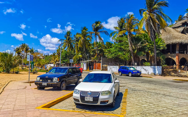 Puerto Escondido Oaxaca Mexico 24. March 2023 Typical beautiful colorful tourist street road and sidewalk with city life cars traffic buildings hotels bars restaurants and people in Zicatela Mexico. - Fotografie, Obrázek