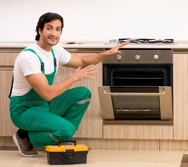 台所でオーブンを修理する若い請負業者 - 写真・画像