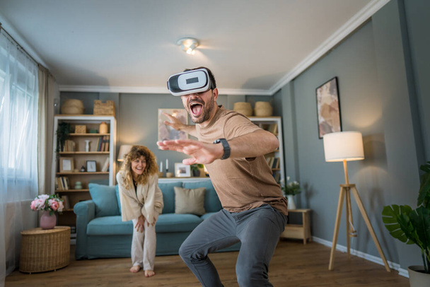 mężczyzna Dojrzałe dorosły biały mężczyzna mąż z jego żona lub dziewczyna para w domu cieszyć się wirtualną rzeczywistość VR zestaw słuchawkowy z google na głowie zabawy nowoczesne technologie wypoczynek koncepcja kopia przestrzeń - Zdjęcie, obraz