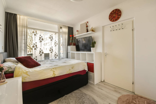 una camera da letto con letto, scrivania e televisione sul muro di fronte al letto è decorata con fiori - Foto, immagini