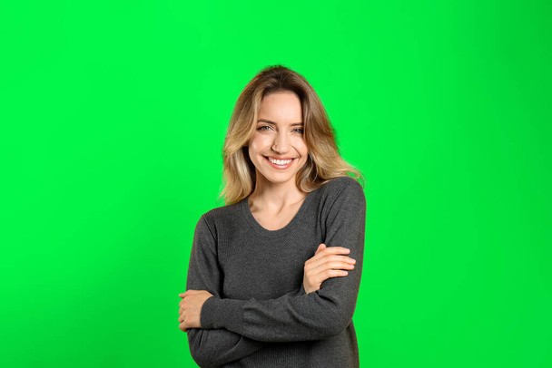 Chroma key compositing. Pretty young woman smiling against green screen - Foto, Imagen