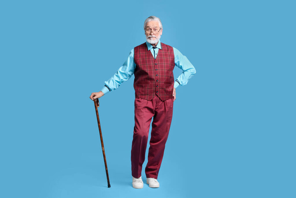 Senior man with walking cane on light blue background - Fotoğraf, Görsel