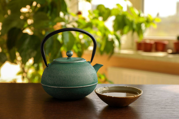 Teapot and cup of freshly brewed tea on wooden table indoors. Traditional ceremony - Фото, зображення