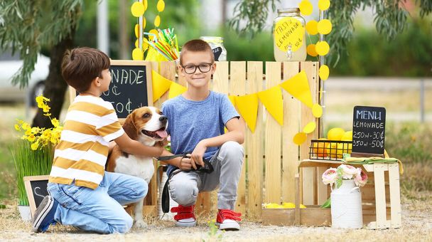 Crianças pequenas bonitos com cão perto de estande de limonada no parque - Foto, Imagem