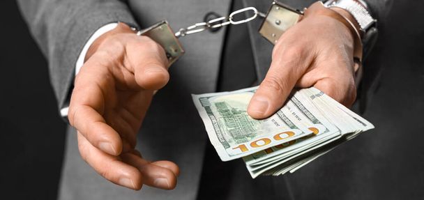 Handcuffed businessman with bribe on dark background, closeup - Photo, Image