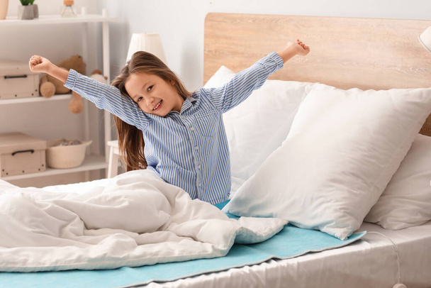 Meisje stretching op elektrische verwarming pad in de slaapkamer - Foto, afbeelding