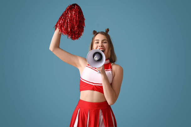 Kaunis cheerleader huutaa megafoniksi sinisellä taustalla - Valokuva, kuva