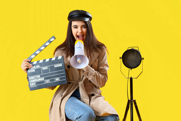 Γυναίκα σκηνοθέτης με ταινία που φωνάζει σε μεγάφωνο σε κίτρινο φόντο - Φωτογραφία, εικόνα