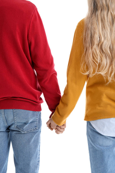 Teenage couple holding hands on white background, back view - Foto, imagen