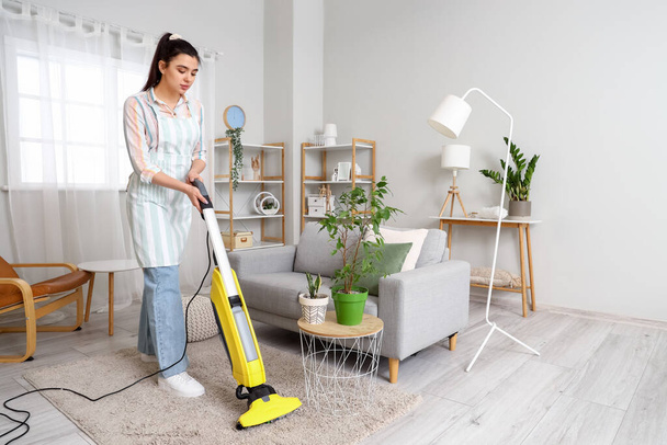Young woman hoovering floor in her house - Photo, Image