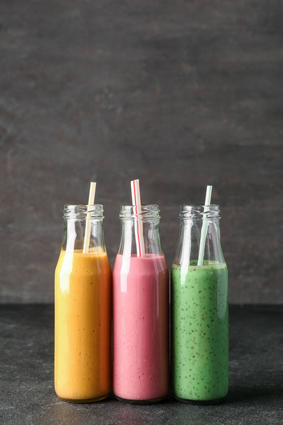 Bottles of colorful smoothie on dark table - Zdjęcie, obraz