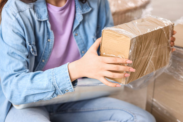 Young woman wrapping cardboard box with stretch film at home on moving day, closeup - Photo, Image