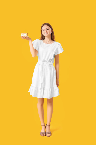 Красивая молодая женщина с тортом на желтом фоне - Фото, изображение