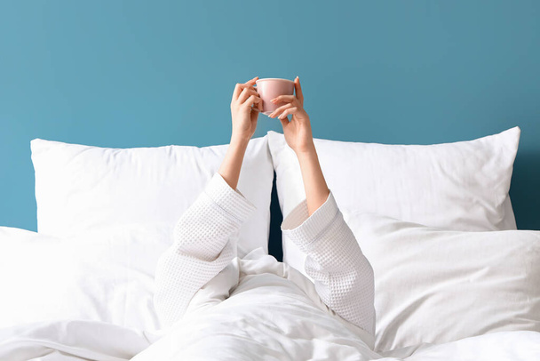 Egy fiatal nő reggele egy csésze kávéval az ágyban - Fotó, kép