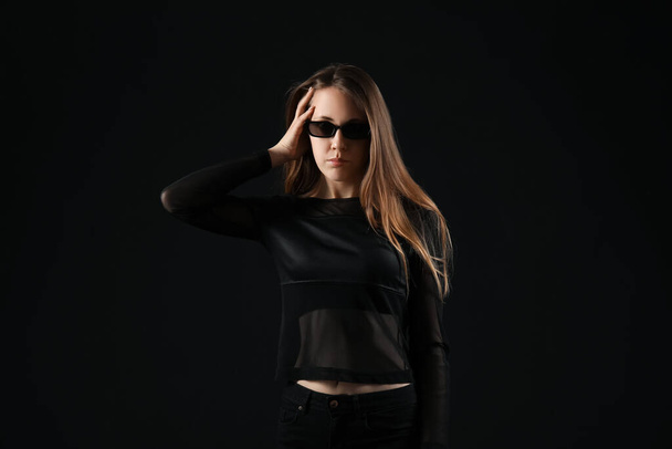 Mujer joven en gafas de sol sobre fondo oscuro
 - Foto, imagen