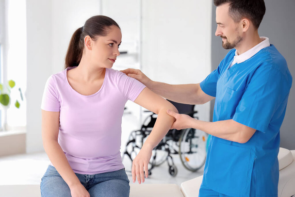 Male physiotherapist working with young woman in rehabilitation center - Zdjęcie, obraz