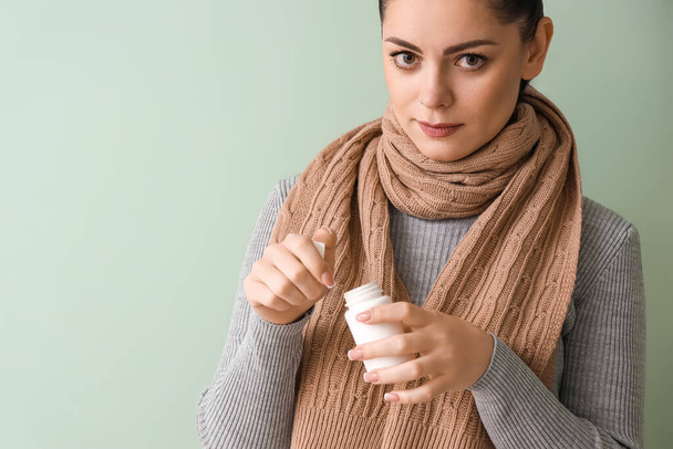 Ill young woman with pill bottle on green background, closeup - Foto, afbeelding