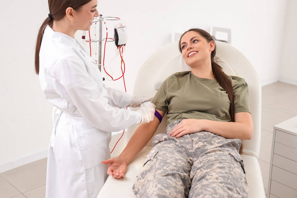 Médecin préparant une femme soldat pour une transfusion sanguine en clinique - Photo, image