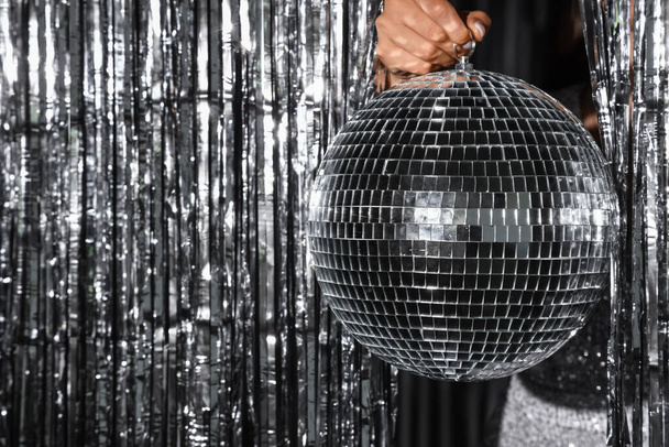 Woman holding disco ball against silver tinsel - Foto, Imagem