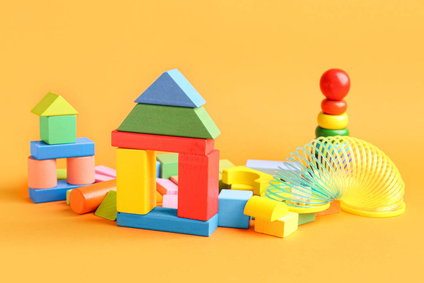 Verschiedene bunte Spielzeuge auf orangenem Hintergrund. Kindertagsfeier - Foto, Bild