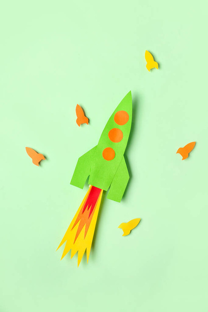 Açık yeşil arkaplanda renkli kağıt roketler - Fotoğraf, Görsel