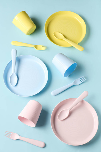 Plates with cups and cutlery for baby on blue background - Foto, afbeelding