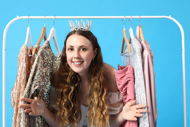 Young woman in crown with prom dresses on blue background - 写真・画像