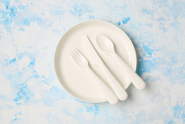 Λευκό πιάτο με μαχαιροπήρουνα για το μωρό σε grunge μπλε φόντο - Φωτογραφία, εικόνα