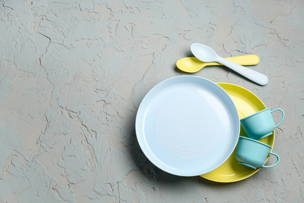 Tazze con piatti e cucchiai su fondo grigio grunge - Foto, immagini