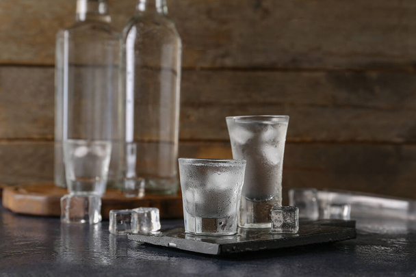 Shots and bottles of vodka on dark table - Photo, Image