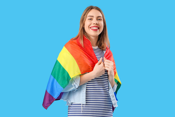 Mladá žena s LGBT vlajkou na modrém pozadí - Fotografie, Obrázek