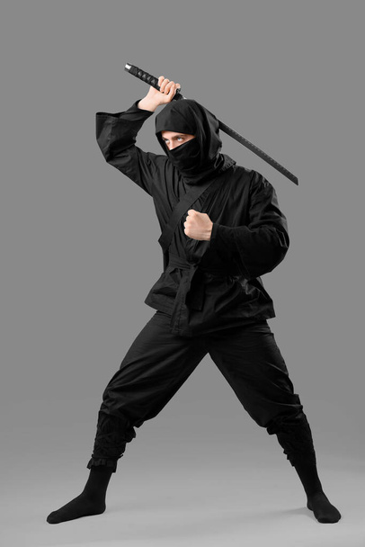 Male ninja with sword on grey background - Zdjęcie, obraz