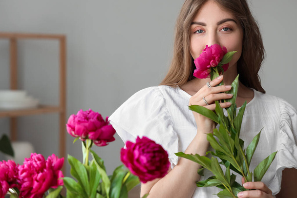 Kaunis nuori nainen kukkakimppu pioni kukkia keittiössä - Valokuva, kuva