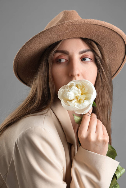 Beautiful young woman with peony flower on grey background - Fotografie, Obrázek