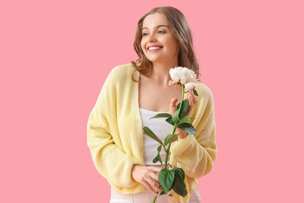 Mooie jonge vrouw met boeket van pioenroos bloemen op roze achtergrond - Foto, afbeelding