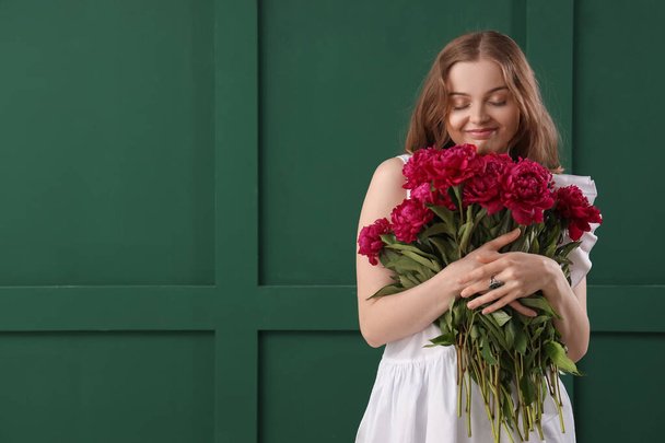 Schöne junge Frau mit Strauß von Pfingstrosen Blumen auf grünem Hintergrund - Foto, Bild