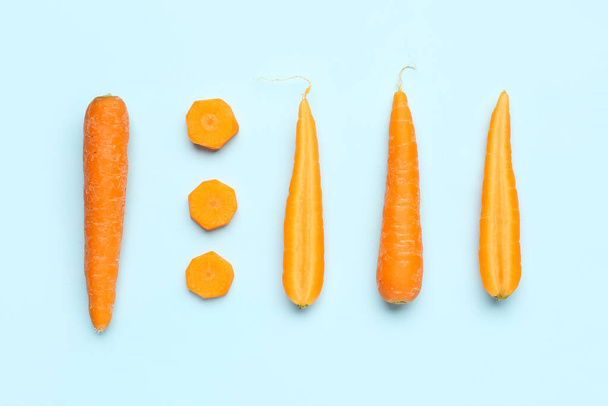 Fresh carrots and slices on turquoise background - 写真・画像