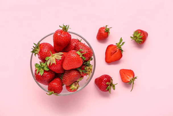 Glass bowl with fresh strawberries on pink background - 写真・画像