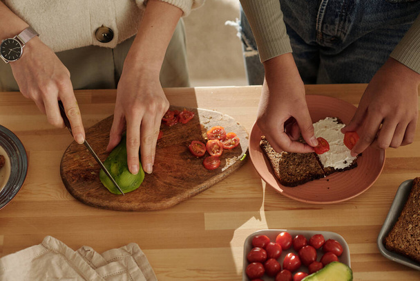 Nagy látószögű kilátás anya főzés szendvicsek zöldségek együtt lányával konyhaasztalnál - Fotó, kép