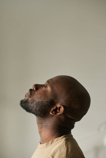 Вертикальное изображение афроамериканца, медитирующего с закрытыми глазами на сером фоне - Фото, изображение