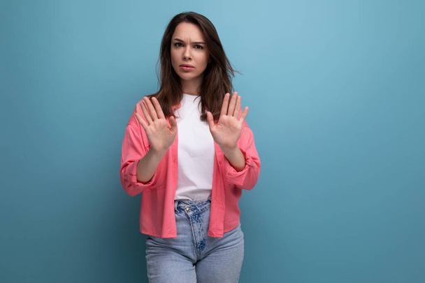 stylish brunette woman in a trendy shirt refuses an offer on a studio background. - Photo, Image
