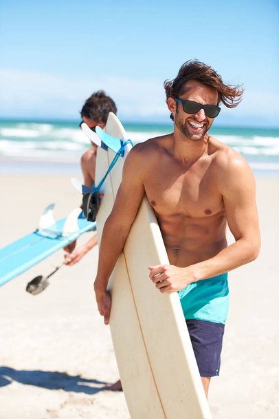 Travel, summer and surfing friends on the beach together together for vacation or holiday trip overseas. Surf, ocean or fun with a young man surfer in sunglasses and friend bonding outdoor by the sea. - Foto, imagen