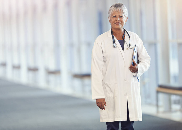 Portrait, healthcare and documents with a senior doctor standing in a hospital corridor for insurance or treatment. Medical, trust and paperwork with a woman medicine professional in a health clinic. - Foto, Bild