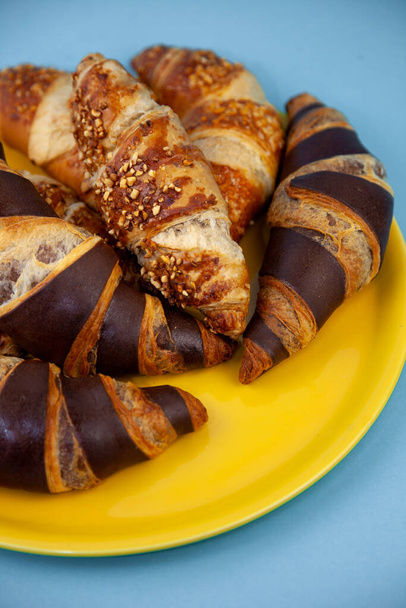 Chocolate croissants or croissant with nut crumbs on a plate. Delicious breakfast on the table. Tasty sweet baking dessert for coffee. Food background. Fresh buttery croissants rolls - Foto, afbeelding